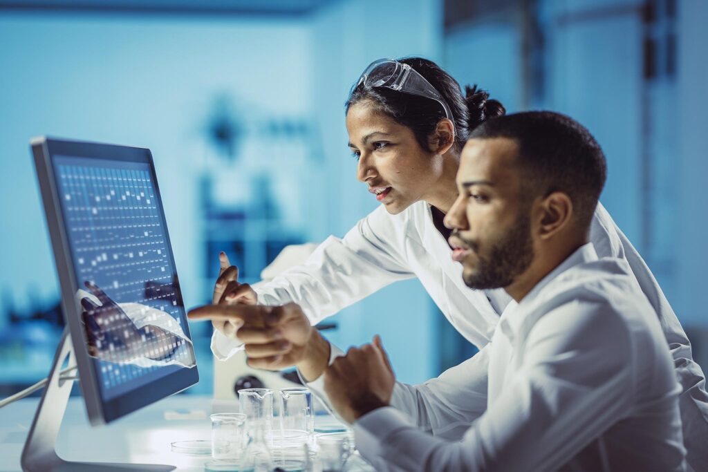 Des employés de laboratoire regardent un écran d'ordinateur.