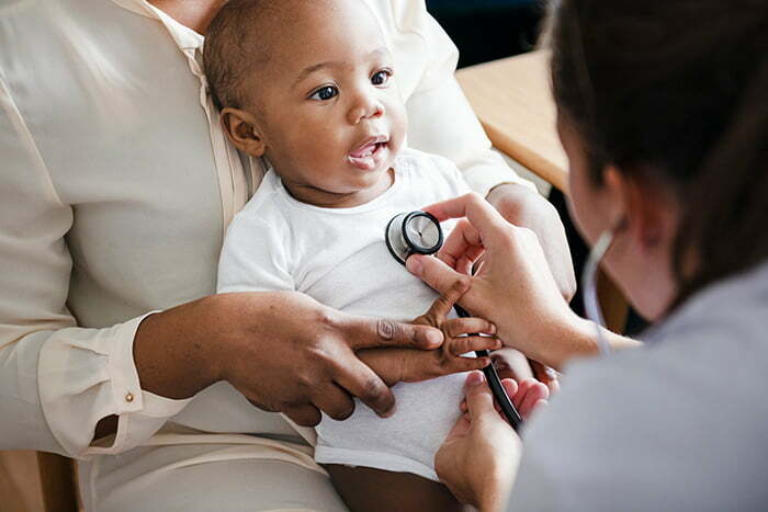 Doctor checking baby's heart with stethoscope.